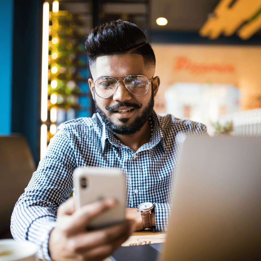 man sitting in front of computer holding phone